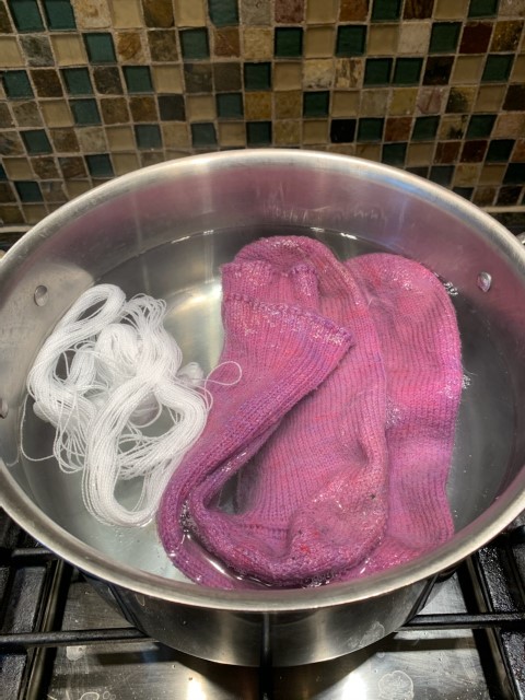 A photo of thread and a pair of socks in the pre-wetting vinegar and water solution.